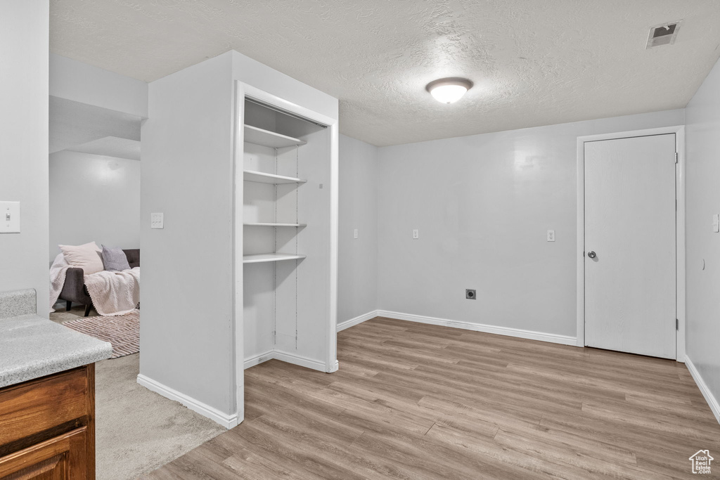 Unfurnished bedroom with light wood-style floors, baseboards, and a textured ceiling