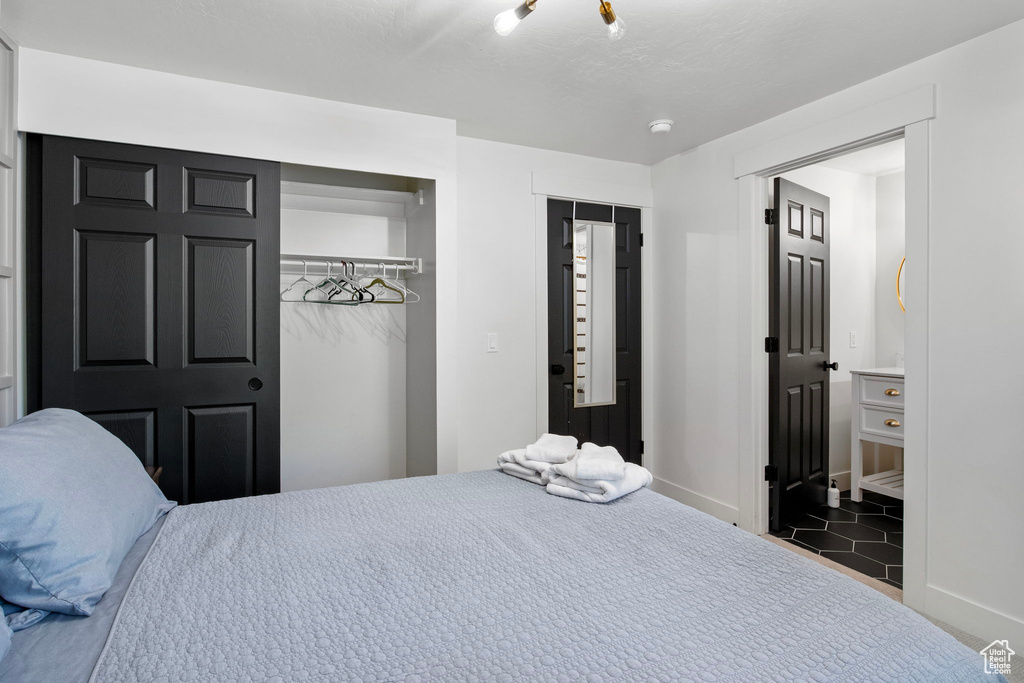 Tiled bedroom featuring a closet, baseboards, and ensuite bath