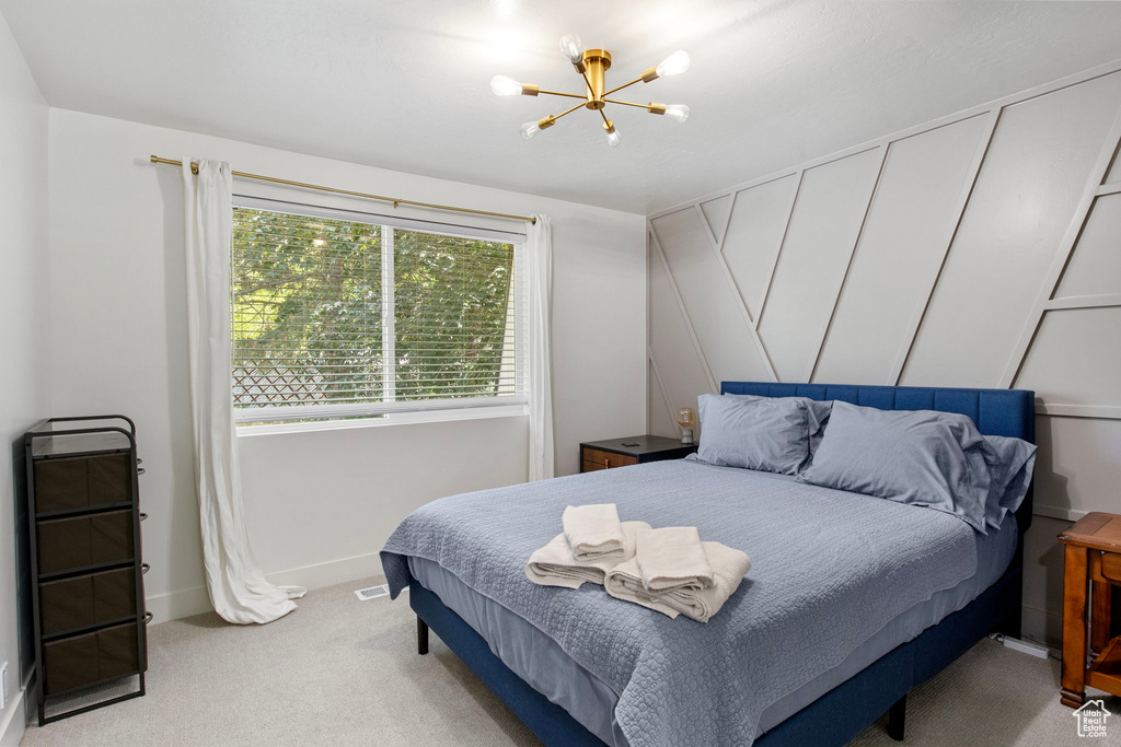 Bedroom with a chandelier, light colored carpet, and baseboards