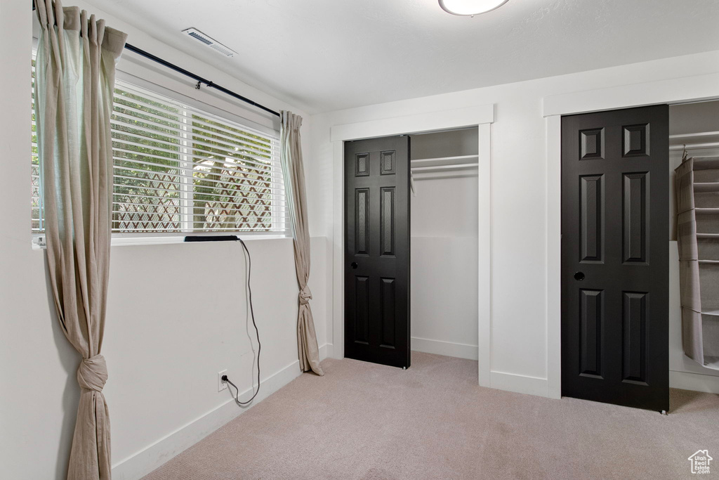 Unfurnished bedroom featuring carpet floors, baseboards, and multiple closets