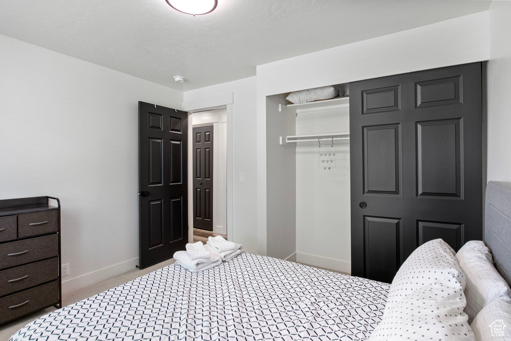 Carpeted bedroom featuring a closet and baseboards