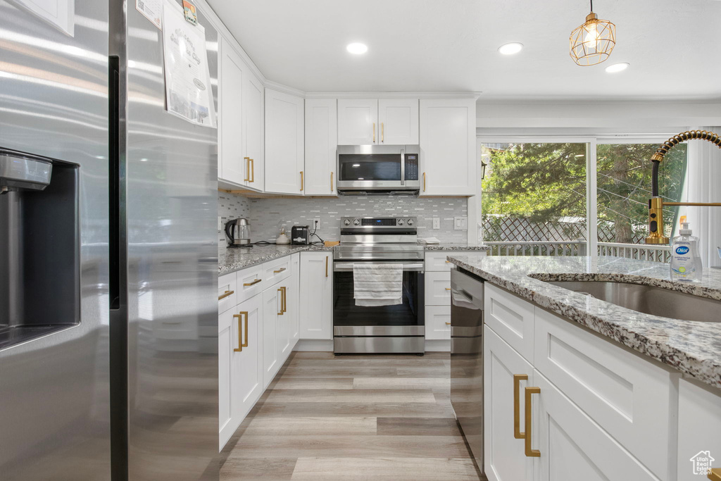Kitchen featuring appliances with stainless steel finishes, a sink, white cabinets, light wood finished floors, and recessed lighting
