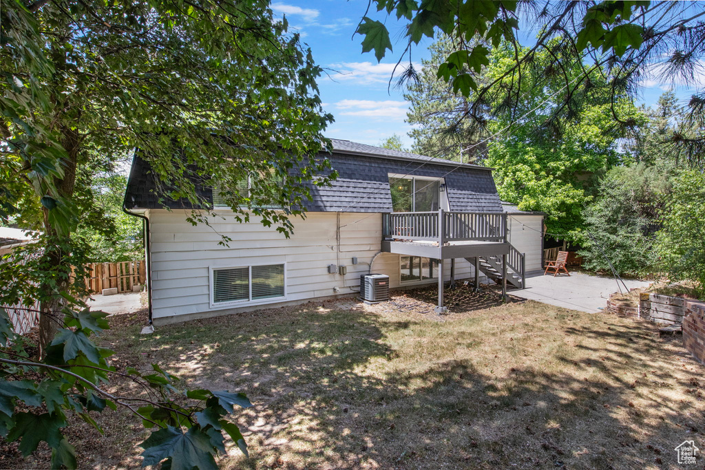 Back of property featuring a deck, central AC unit, a shingled roof, and a patio