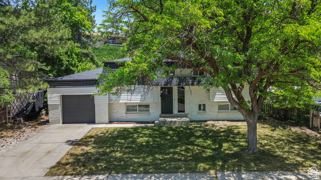 View of front of property with a garage, concrete driveway, brick siding, and a shingled roof