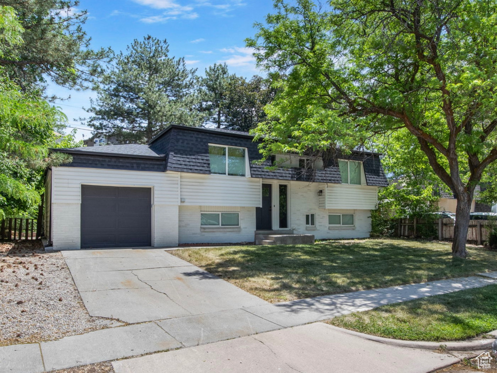 View of front of house with mansard roof, an attached garage, concrete driveway, and roof with shingles