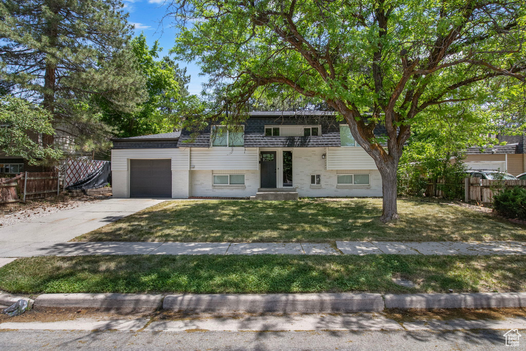 View of front of house featuring concrete driveway, an attached garage, and a balcony