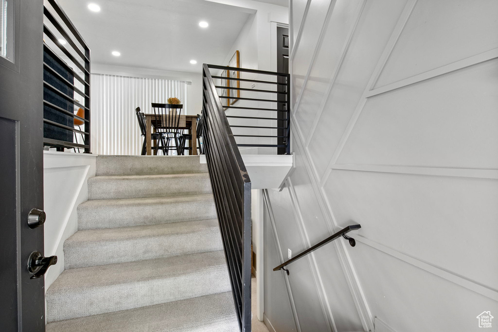 Stairway featuring recessed lighting and a decorative wall