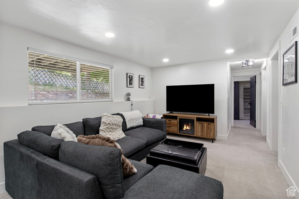 Living area with light carpet, recessed lighting, and baseboards