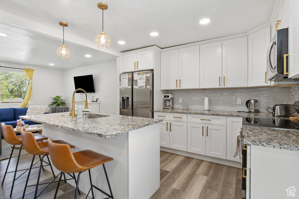 Kitchen with appliances with stainless steel finishes, a sink, backsplash, white cabinetry, and recessed lighting