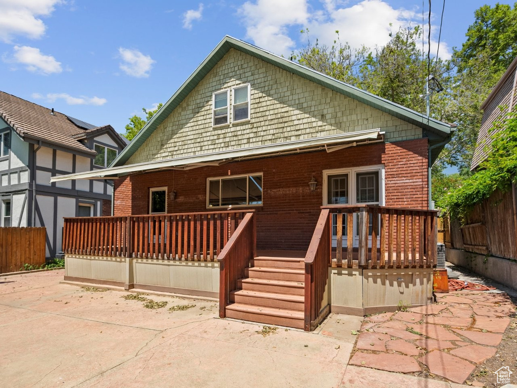 Rear view of house featuring a wooden deck and a patio area