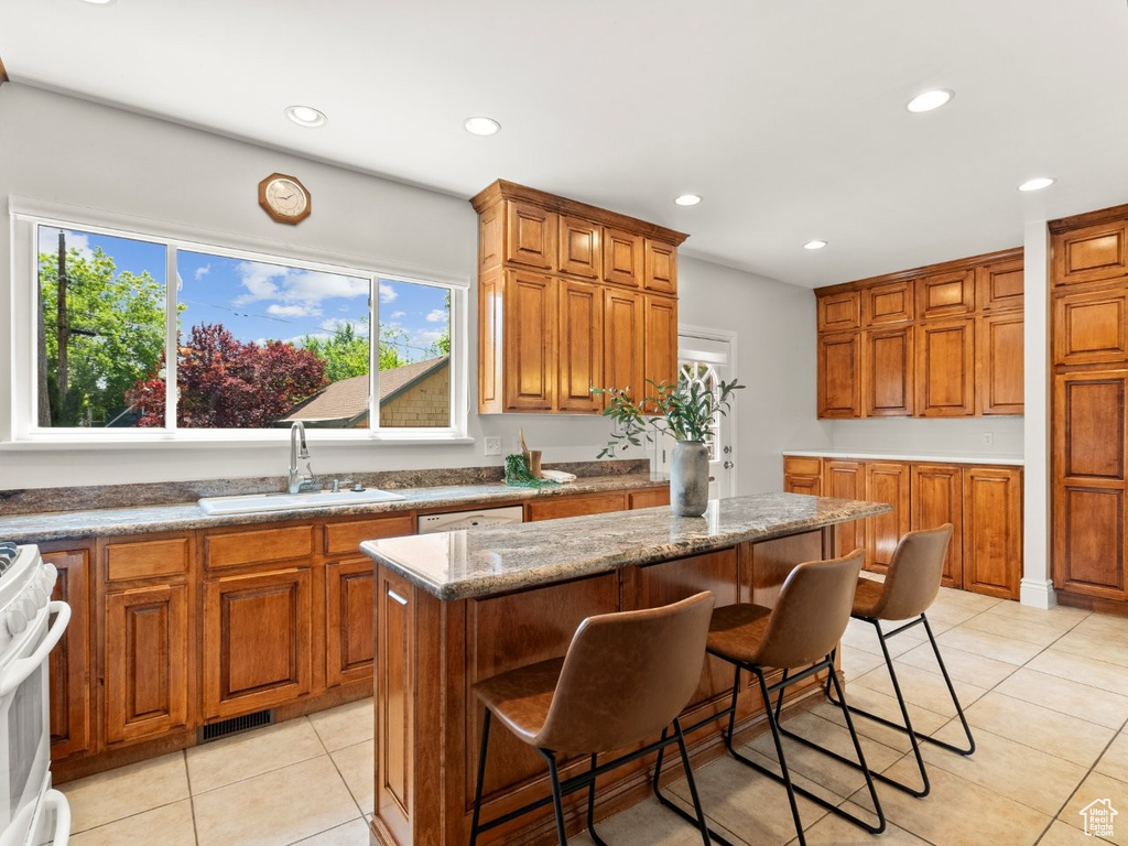 Kitchen with a sink, brown cabinetry, light tile patterned floors, recessed lighting, and plenty of natural light