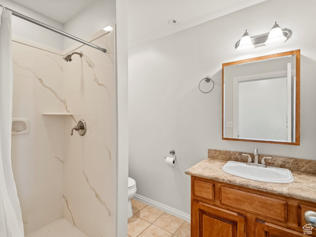Bathroom with vanity, a marble finish shower, toilet, and tile patterned flooring