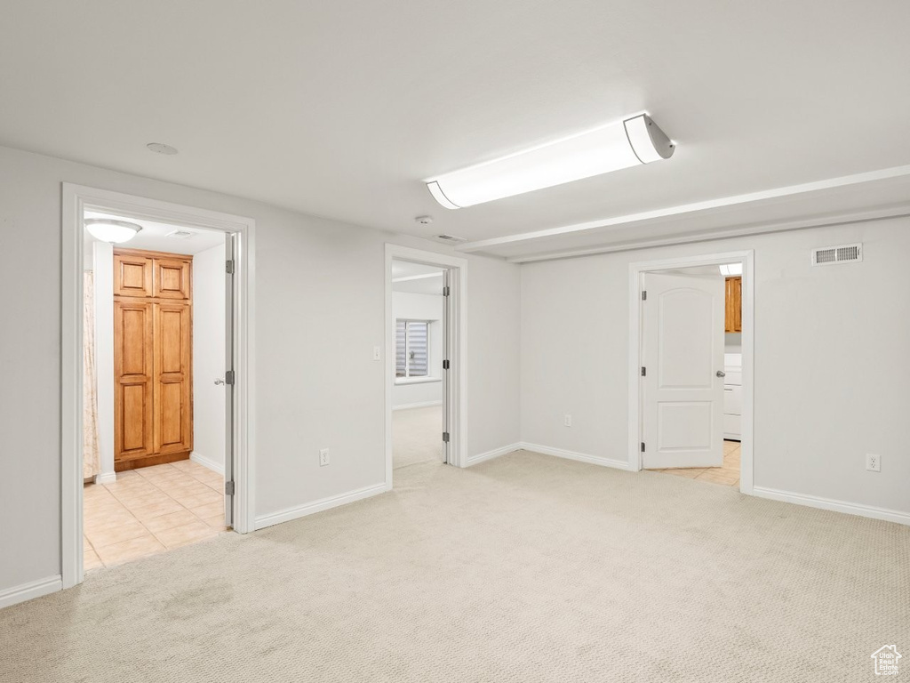 Basement featuring light carpet, baseboards, and light tile patterned floors
