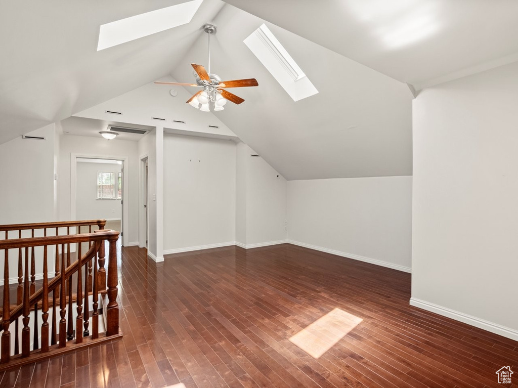 Additional living space with a skylight, lofted ceiling, wood-type flooring, baseboards, and a ceiling fan