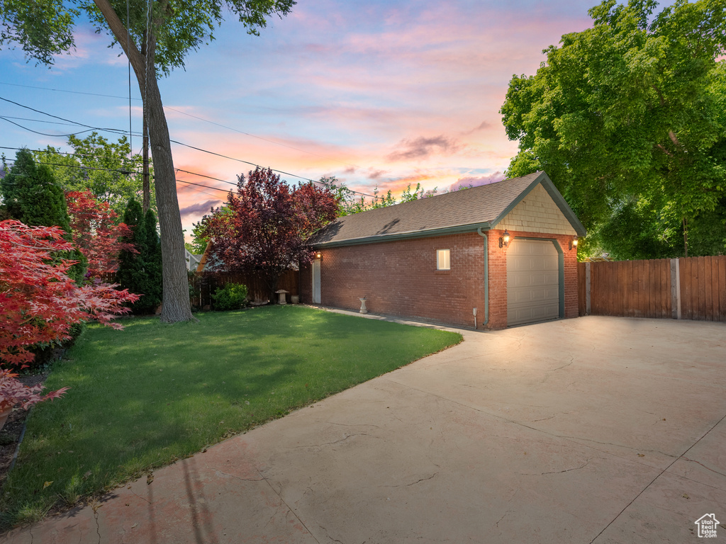 Yard at dusk featuring concrete driveway and a garage