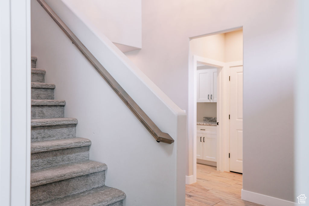 Staircase with wood finished floors and baseboards