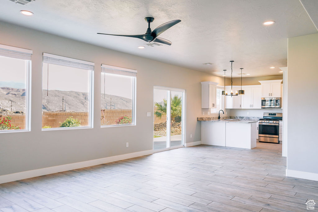 Kitchen with appliances with stainless steel finishes, a sink, open floor plan, baseboards, and light wood finished floors