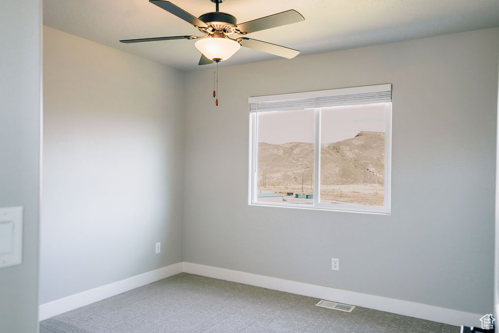 Carpeted spare room with baseboards and a ceiling fan