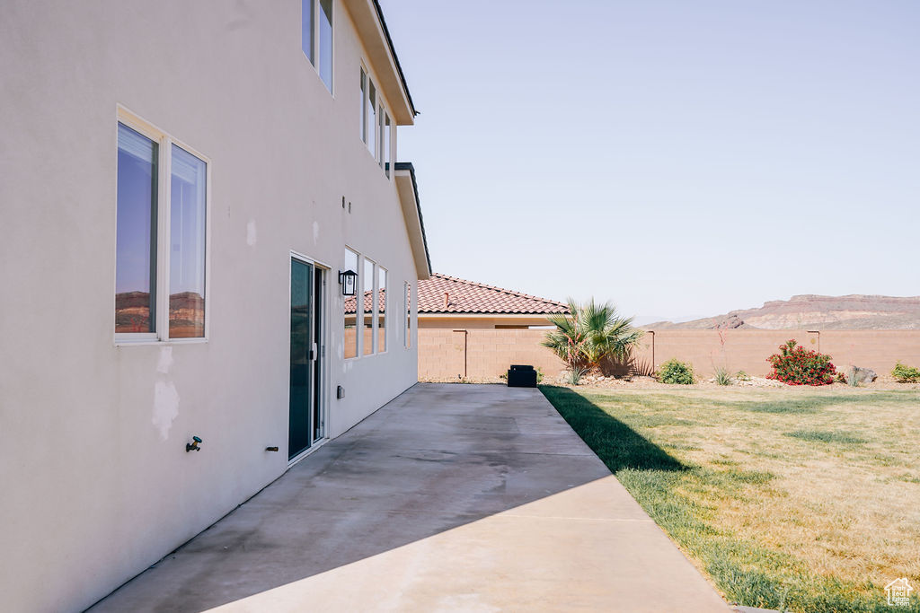 View of side of home featuring stucco siding, a patio, and a mountain view