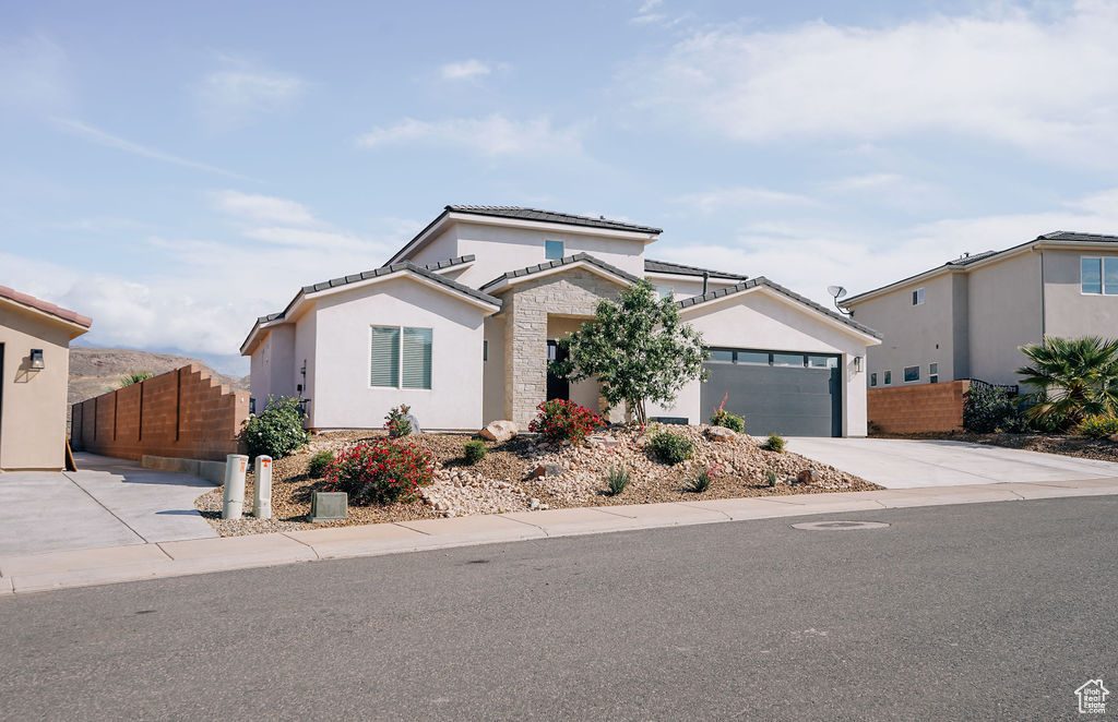 View of front of house with concrete driveway, an attached garage, a tile roof, and stucco siding