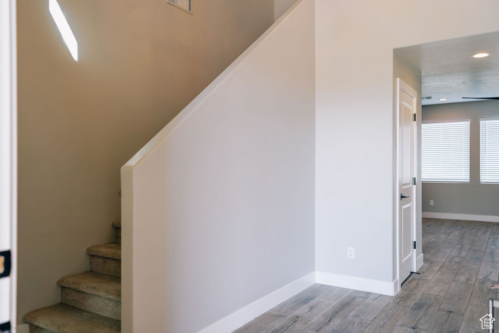 Stairway featuring wood finished floors, baseboards, and recessed lighting