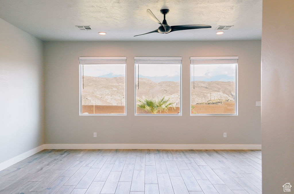 Unfurnished room featuring healthy amount of natural light, ceiling fan, wood finished floors, baseboards, and recessed lighting