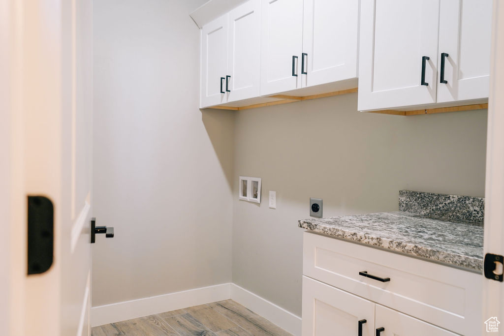 Laundry room featuring hookup for a washing machine, light wood-style flooring, cabinet space, hookup for an electric dryer, and baseboards