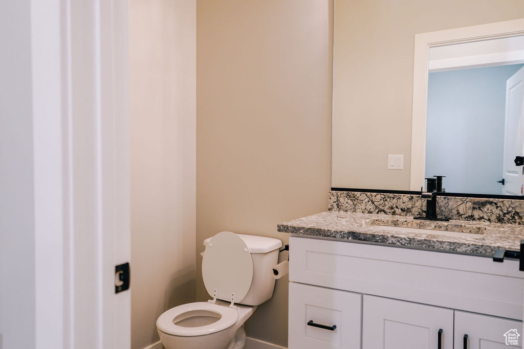 Half bath featuring vanity, toilet, and baseboards