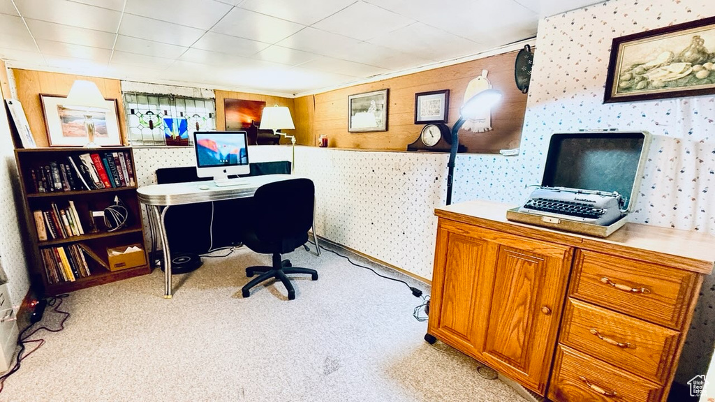 Home office with light colored carpet and wallpapered walls