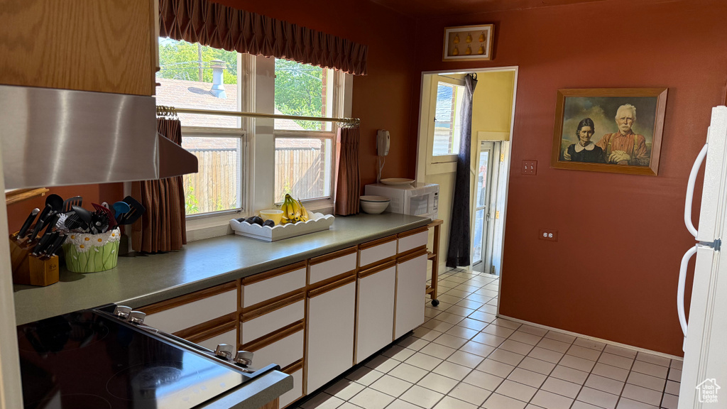 Kitchen featuring freestanding refrigerator, white cabinetry, light countertops, and light tile patterned floors