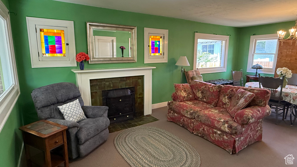 Carpeted living area featuring a chandelier, a tile fireplace, and baseboards