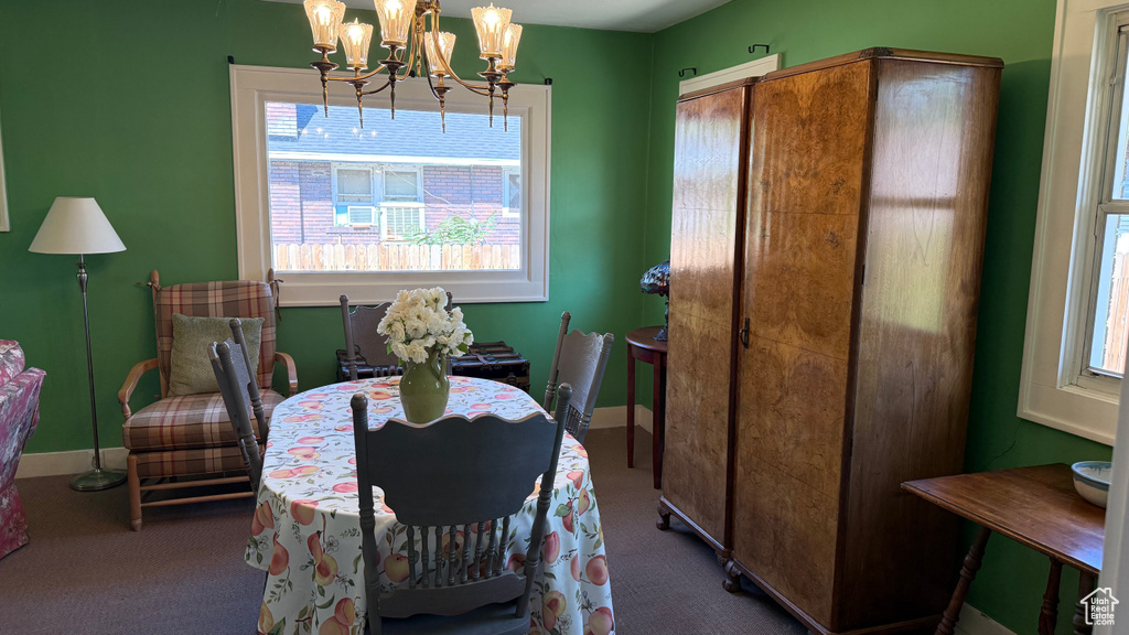 Carpeted dining area featuring healthy amount of natural light, a chandelier, and baseboards