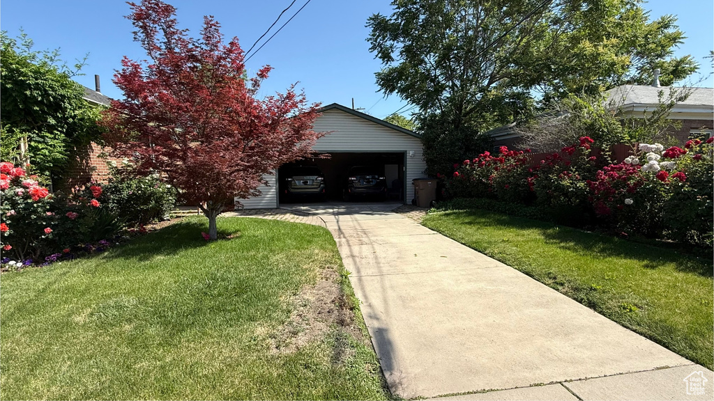 View of green lawn with driveway and an outbuilding
