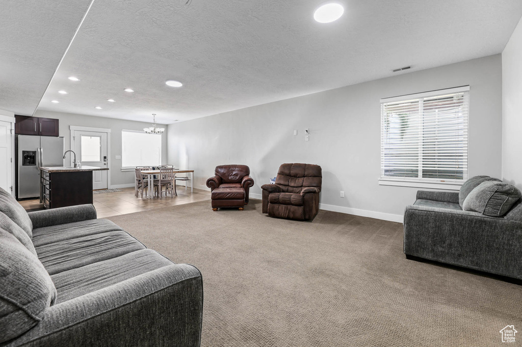 Living room with recessed lighting, baseboards, healthy amount of natural light, a textured ceiling, and a chandelier
