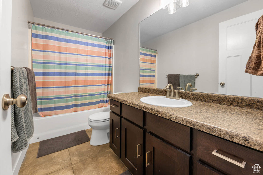 Bathroom with vanity, toilet, shower / bath combo with shower curtain, and tile patterned floors