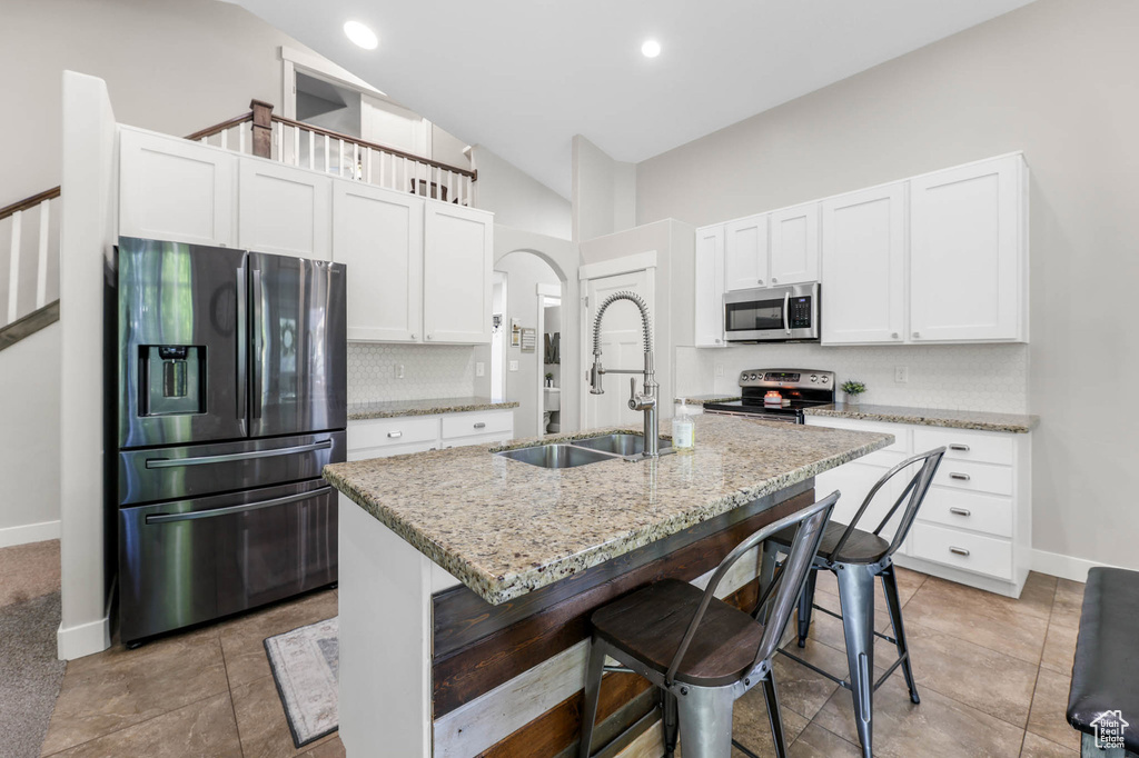 Kitchen with stainless steel appliances, a sink, backsplash, baseboards, and white cabinets
