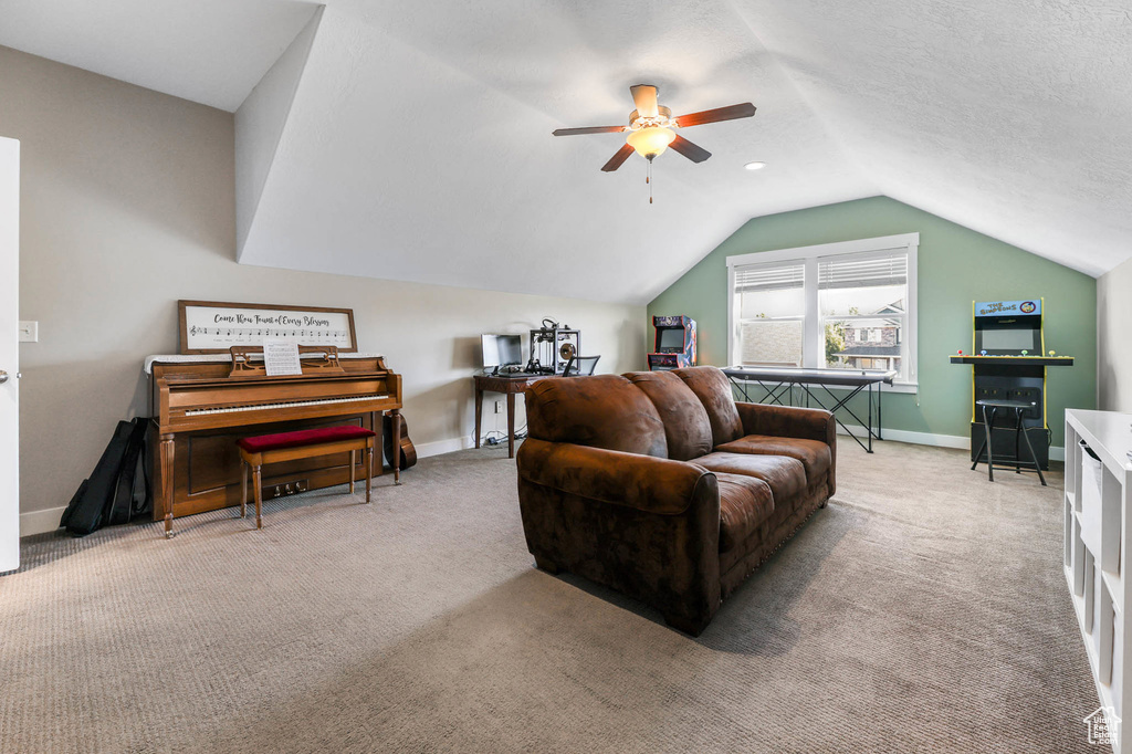 Living area with carpet, vaulted ceiling, a ceiling fan, and baseboards