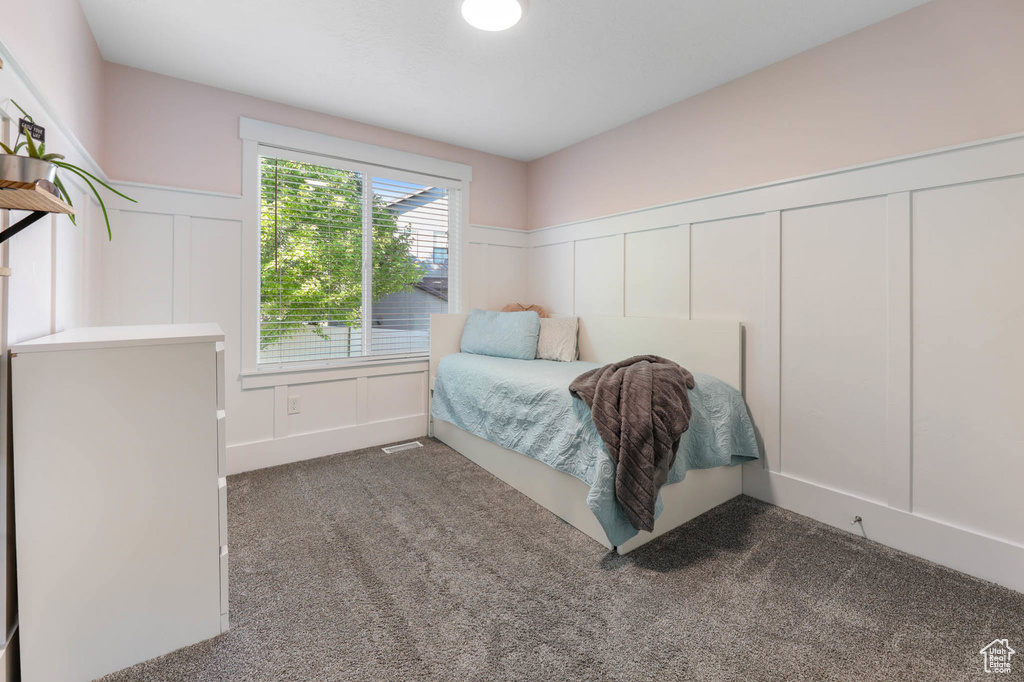 Carpeted bedroom with a decorative wall and wainscoting