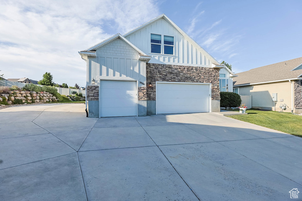 Contemporary house with board and batten siding, stone siding, driveway, and a garage