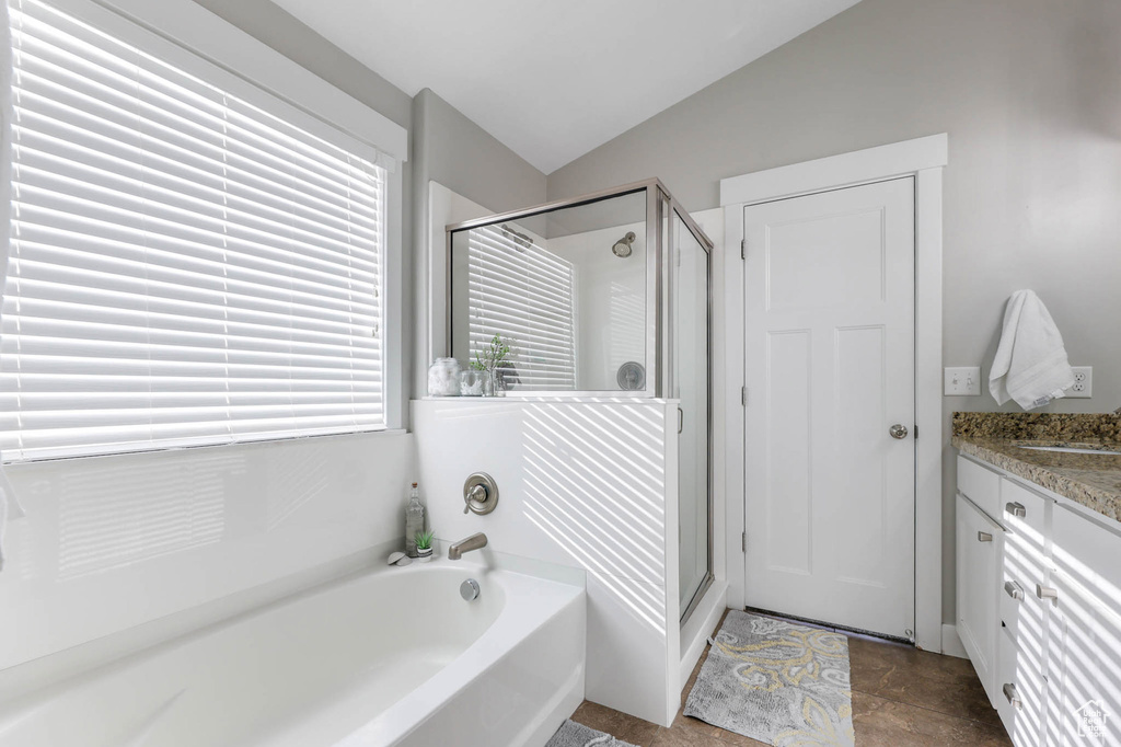 Bathroom featuring lofted ceiling, a garden tub, a stall shower, and vanity