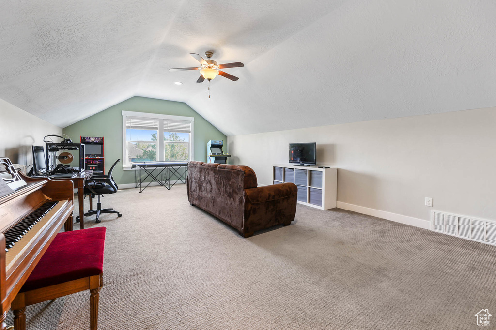 Carpeted office space featuring vaulted ceiling, baseboards, a ceiling fan, and a textured ceiling