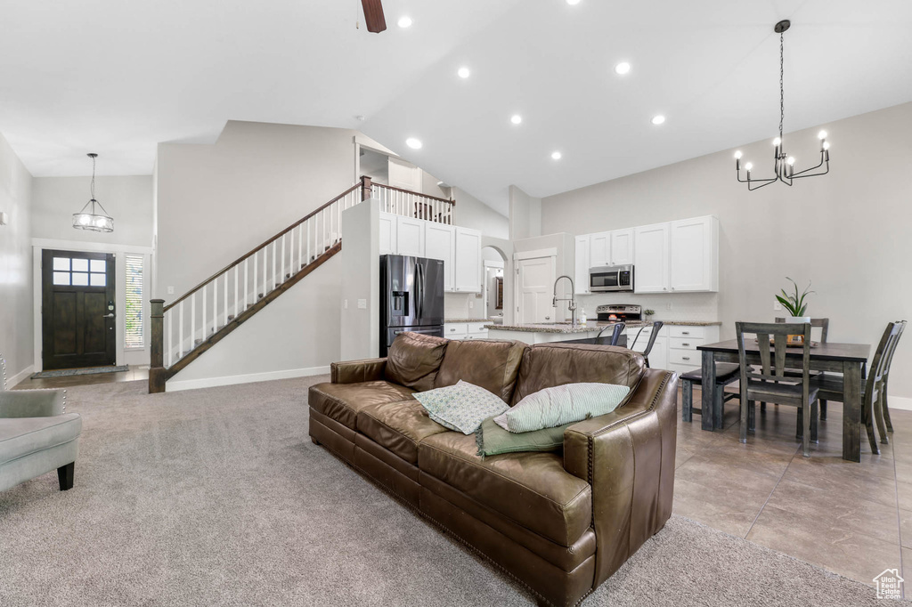 Living area featuring high vaulted ceiling, a chandelier, baseboards, recessed lighting, and stairs