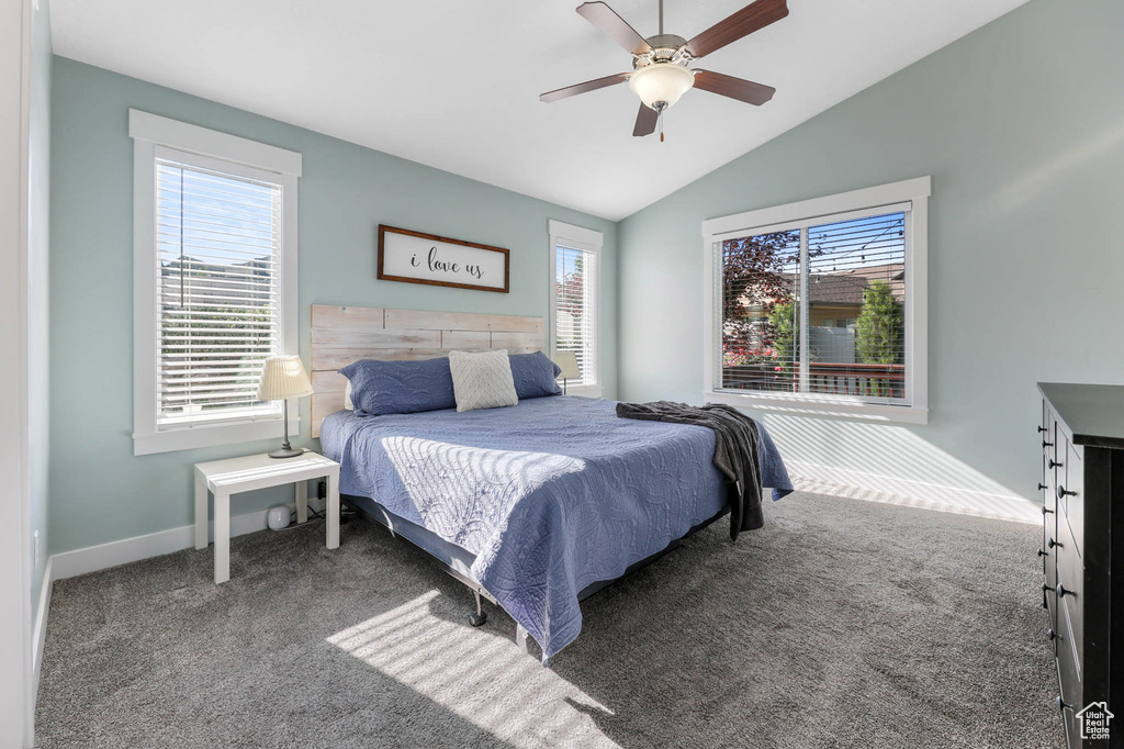 Carpeted bedroom featuring multiple windows, lofted ceiling, baseboards, and a ceiling fan