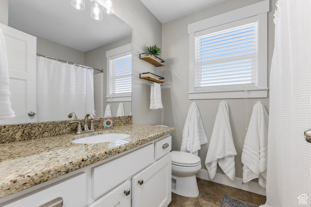 Bathroom featuring toilet, vanity, baseboards, and a shower with shower curtain