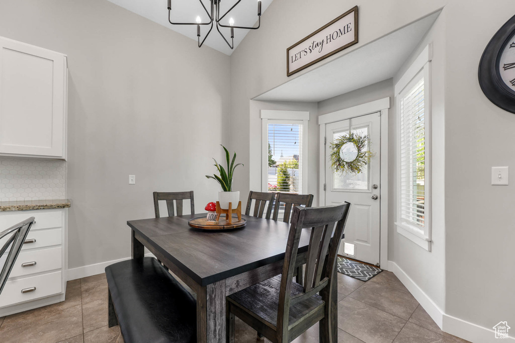 Dining area with baseboards, a chandelier, light tile patterned floors, and high vaulted ceiling