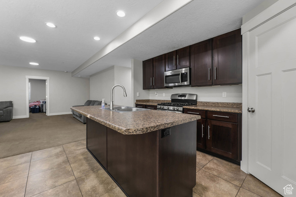 Kitchen with appliances with stainless steel finishes, a sink, open floor plan, recessed lighting, and dark brown cabinets