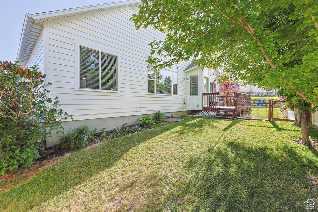 View of grassy yard with a wooden deck