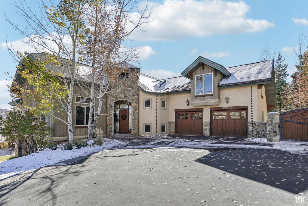 View of front of home with stone siding, stucco siding, driveway, and a garage