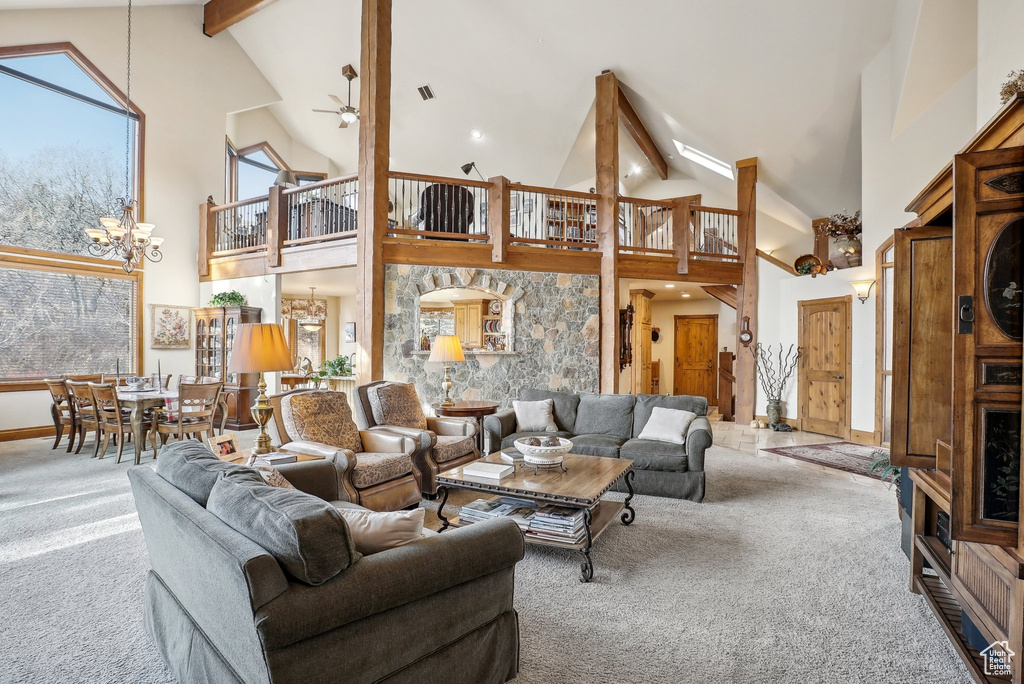 Carpeted living room featuring high vaulted ceiling, beam ceiling, ceiling fan, a chandelier, and baseboards