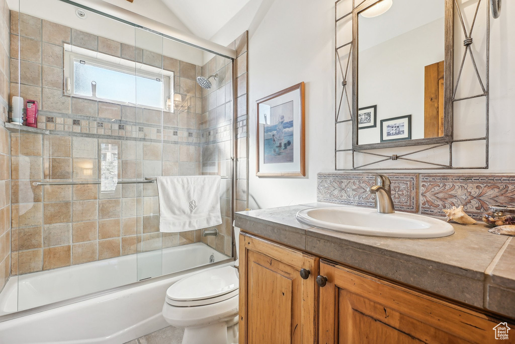 Full bath with toilet, vanity, enclosed tub / shower combo, and tasteful backsplash